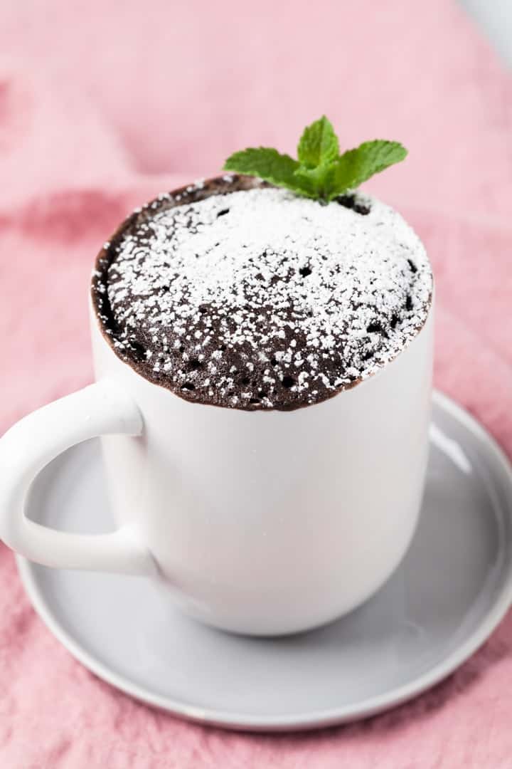 angled view of chocolate mug cake dusted with powdered sugar