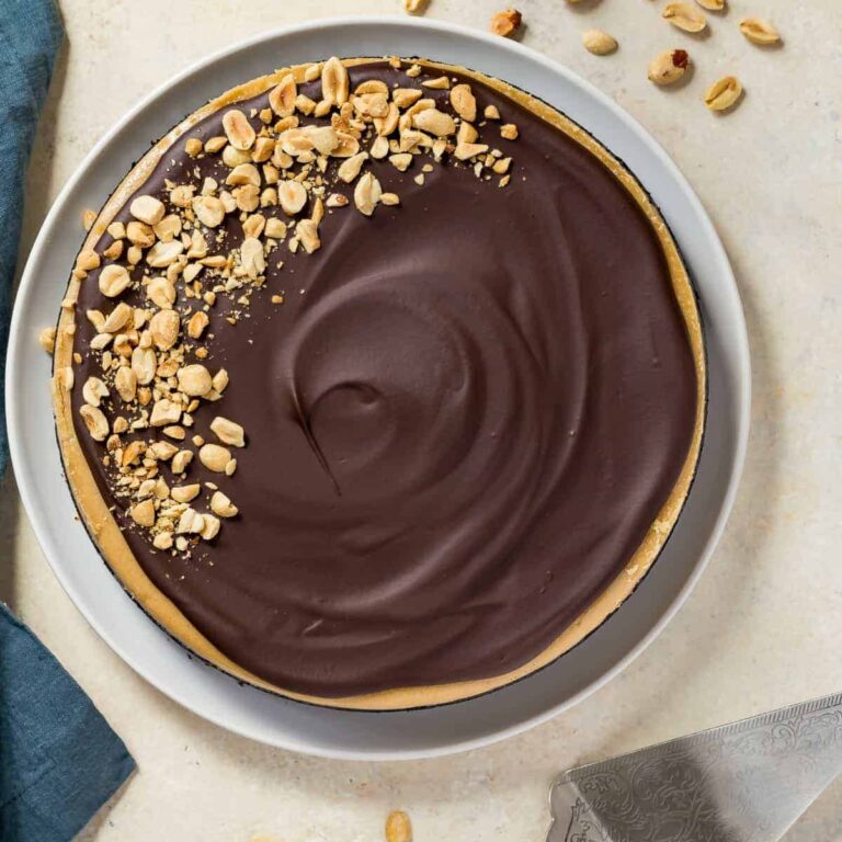 Overhead view of chocolate peanut butter cheesecake on a white plate with a blue napkin beside it.