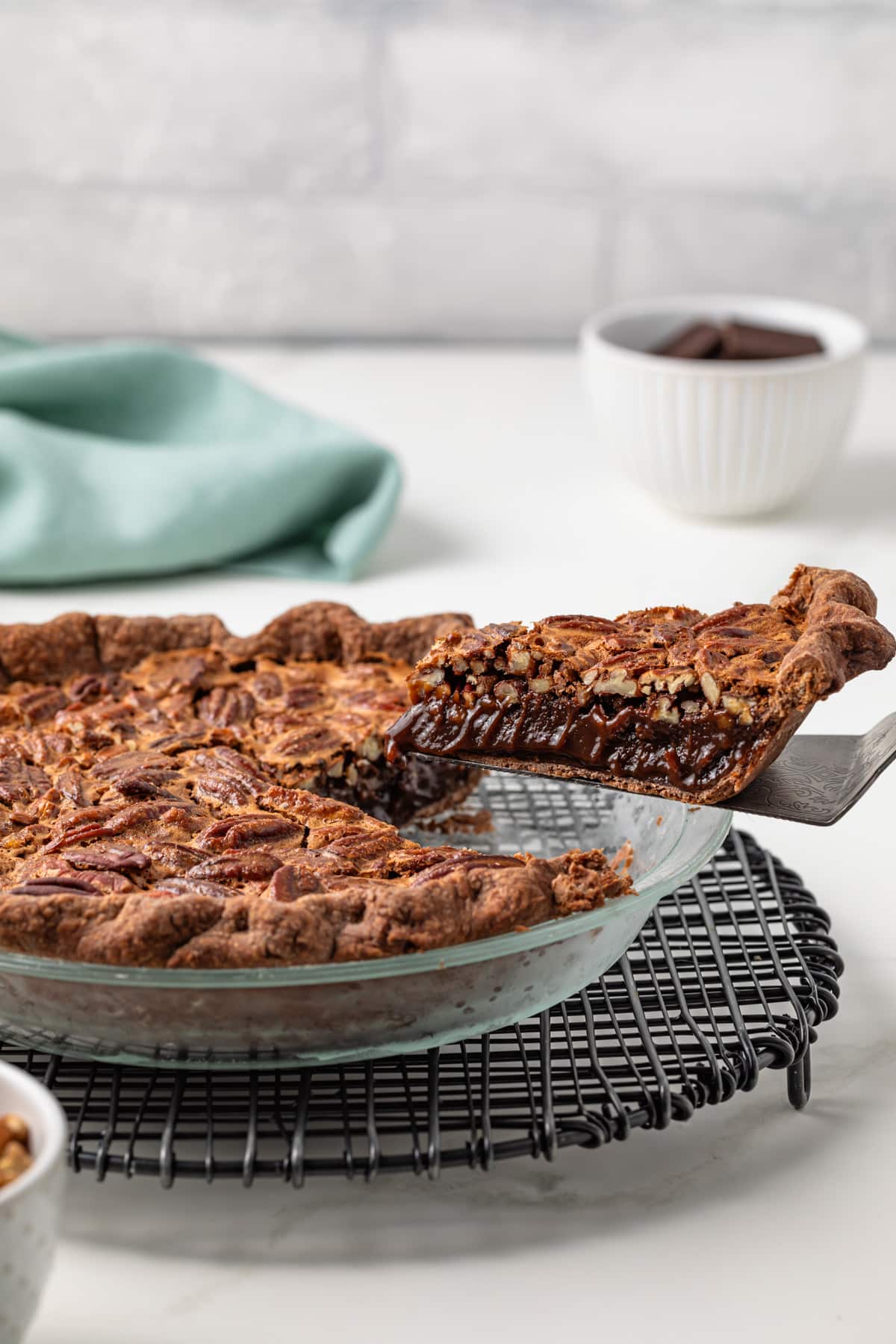 Slice of chocolate pecan pie lifted out of whole pie.