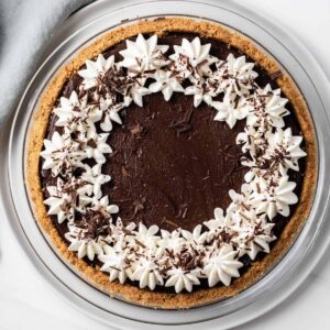 overhead view of chocolate pie topped with whipped cream and chocolate shavings in a glass pie plate
