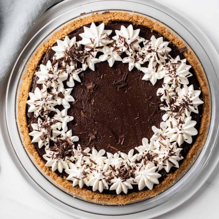 overhead view of chocolate pie topped with whipped cream and chocolate shavings in a glass pie plate
