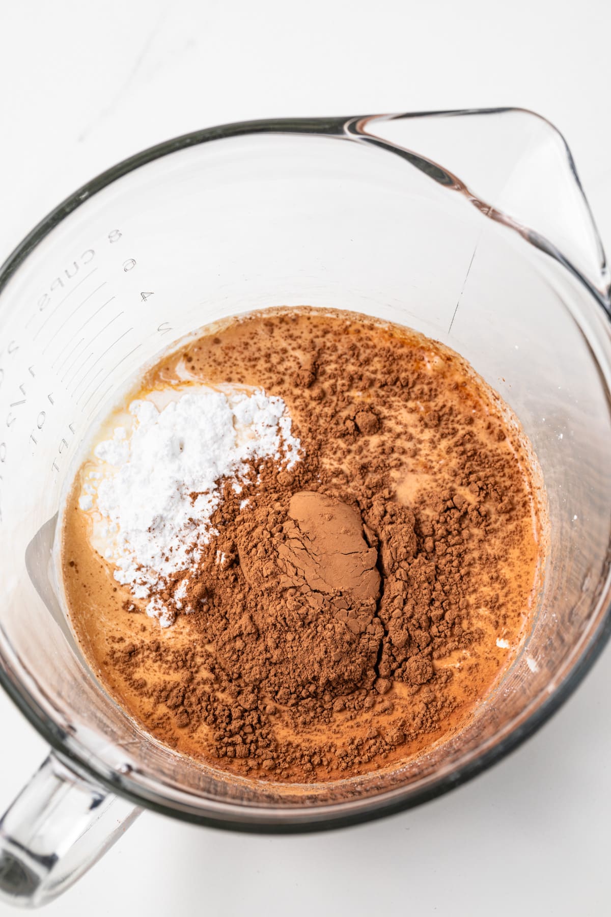 Heavy cream, powdered sugar, and cocoa in a glass bowl.