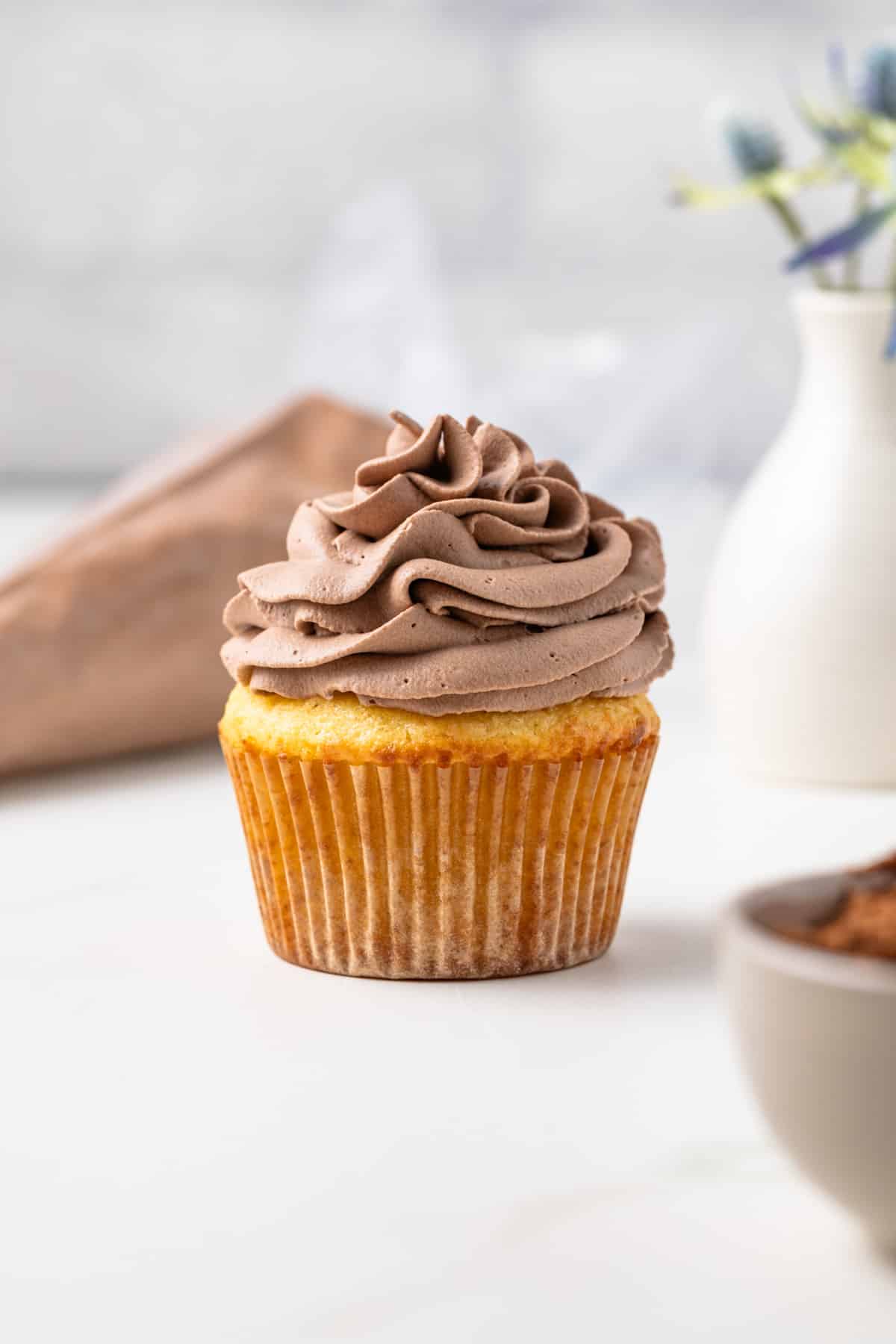 Chocolate whipped cream swirled on a vanilla cupcake.