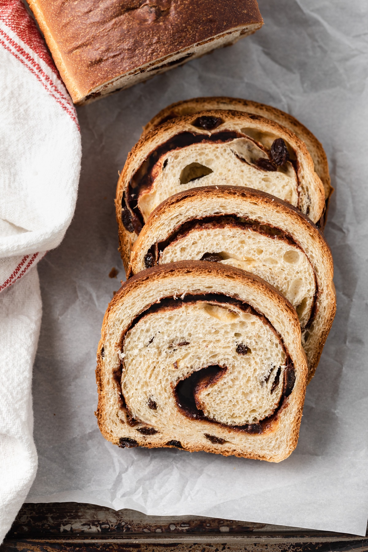 slices of cinnamon raisin bread laid overlapping on baking sheet