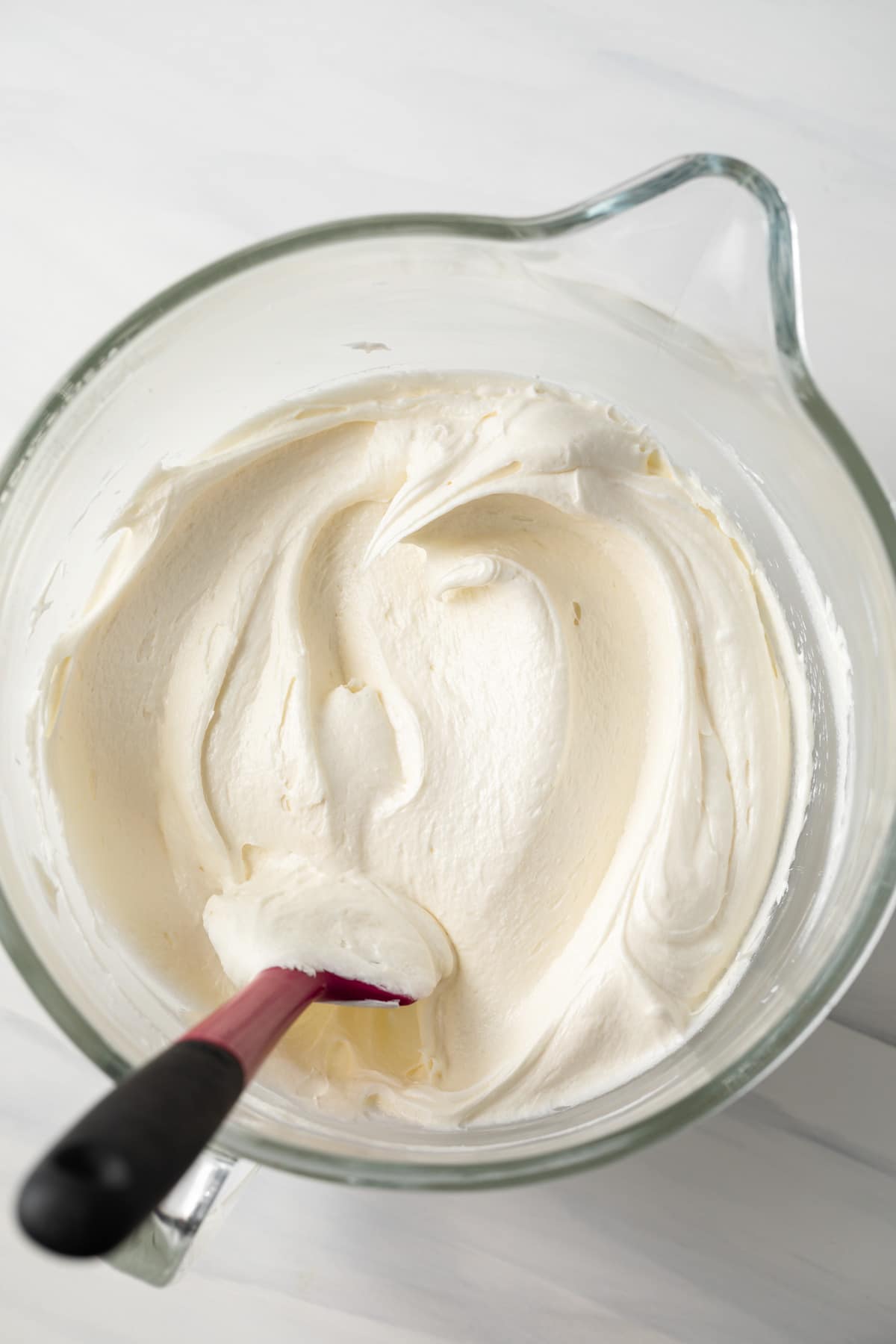 Coconut buttercream frosting in glass mixing bowl.