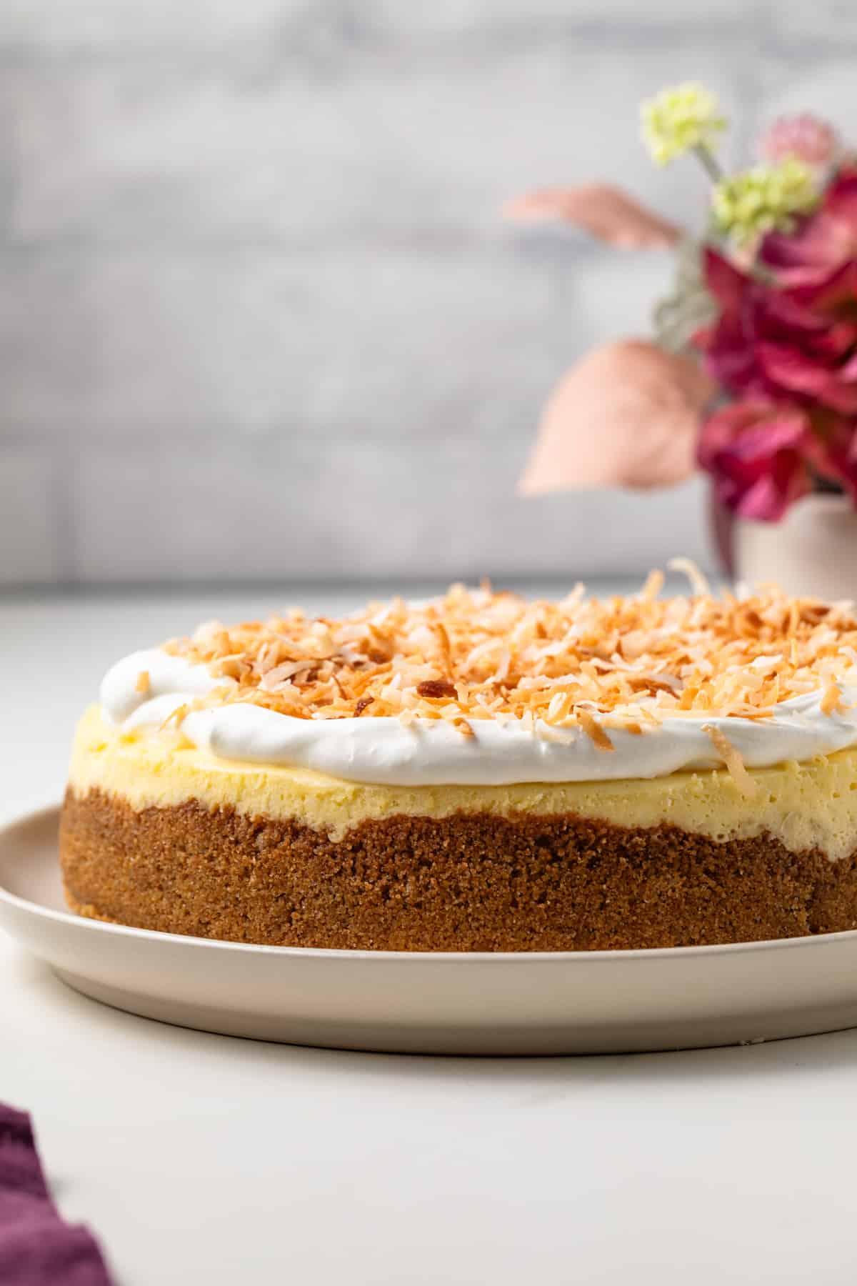 Side view of coconut cheesecake on serving platter.