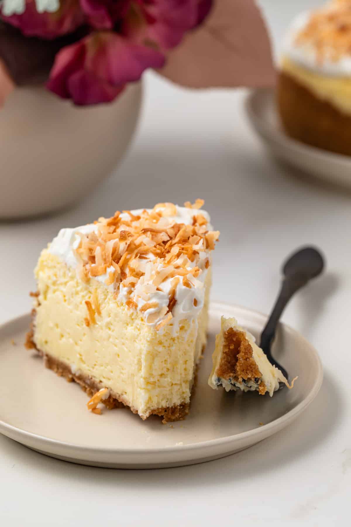 Fork with a bite out of cheesecake on a plate.