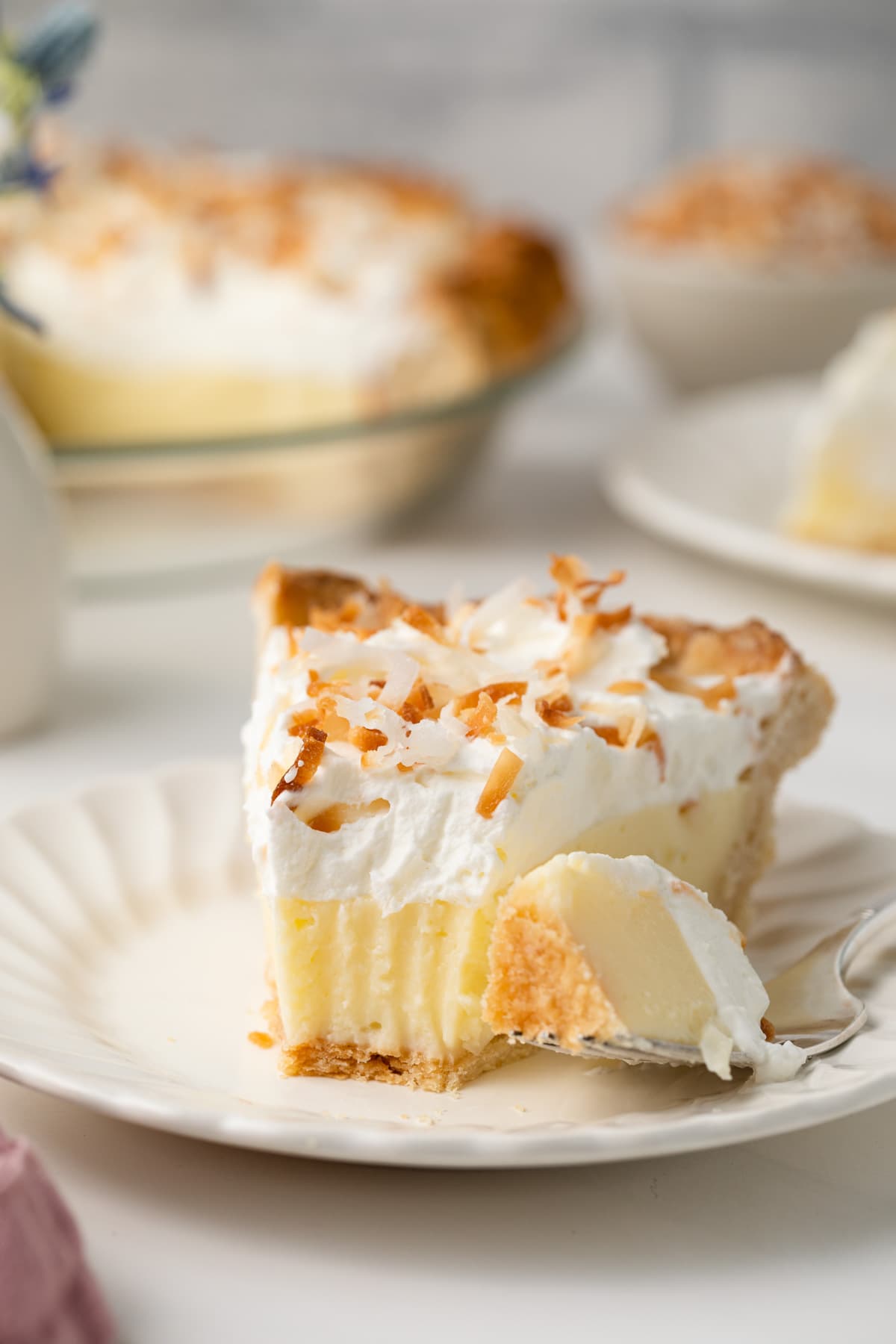 Slice of coconut cream pie with slice taken out.