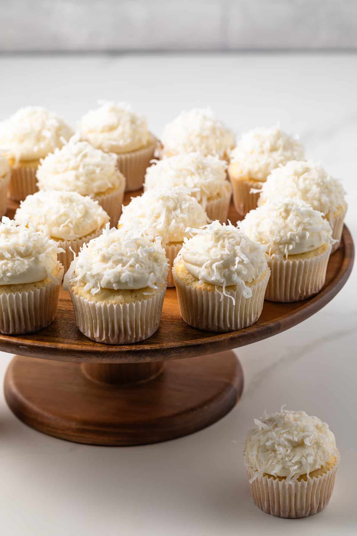 Coconut cupcakes on a wooden cake stand.