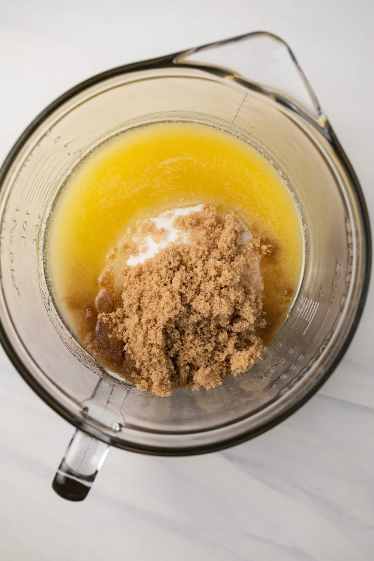 Brown sugar, white sugar, and melted butter in glass bowl.