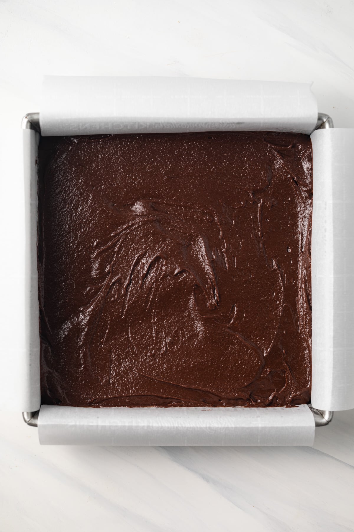 Brownie batter in square baking pan.