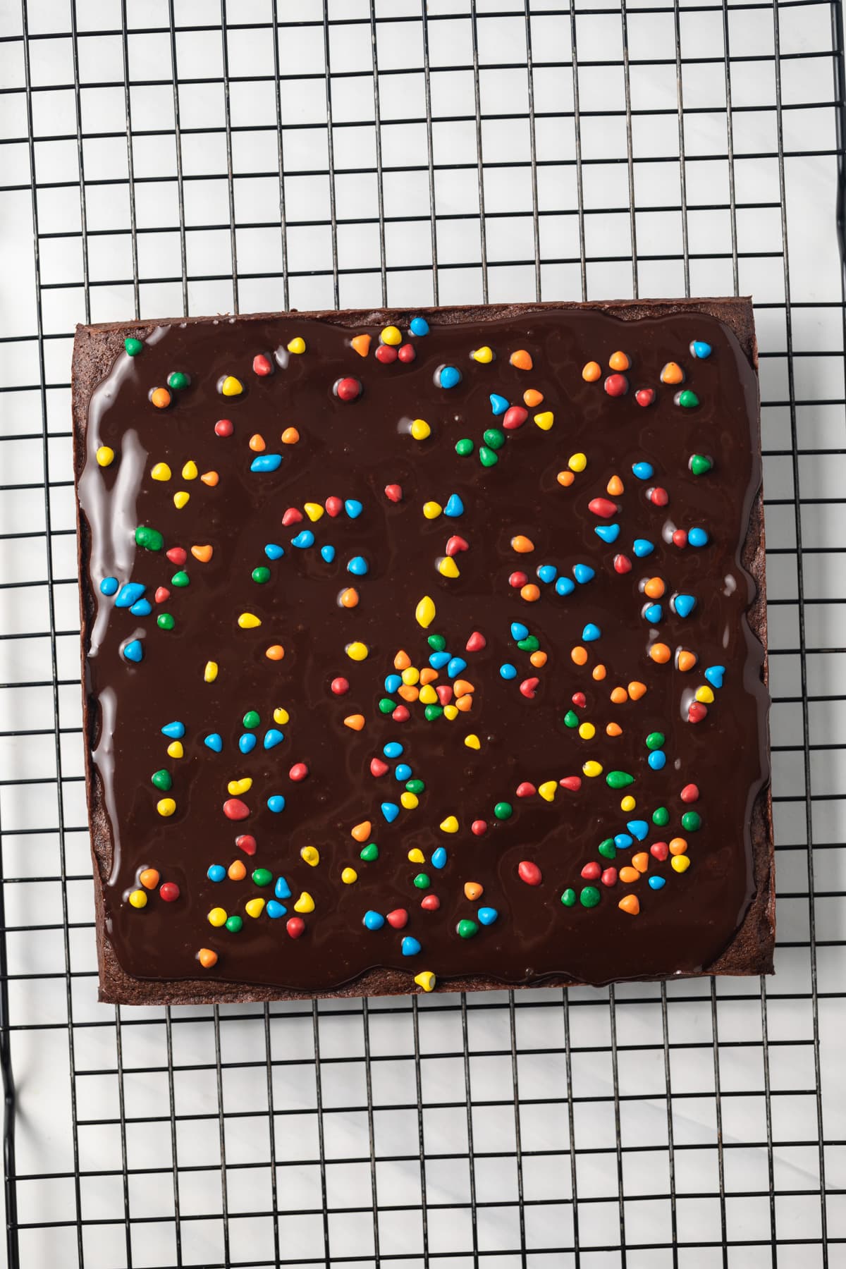 Brownies topped with ganache and rainbow chips.