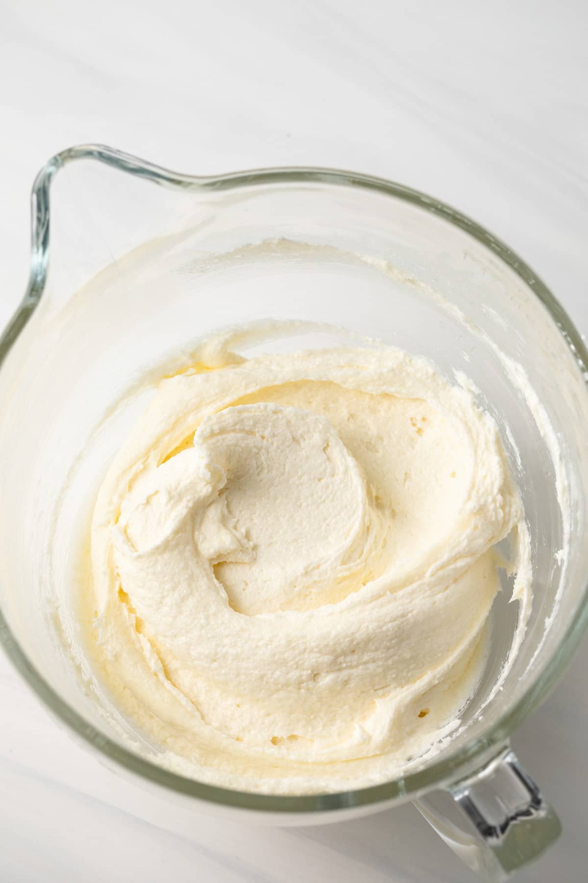 Whipped butter, cream cheese, and sugar in a glass bowl.