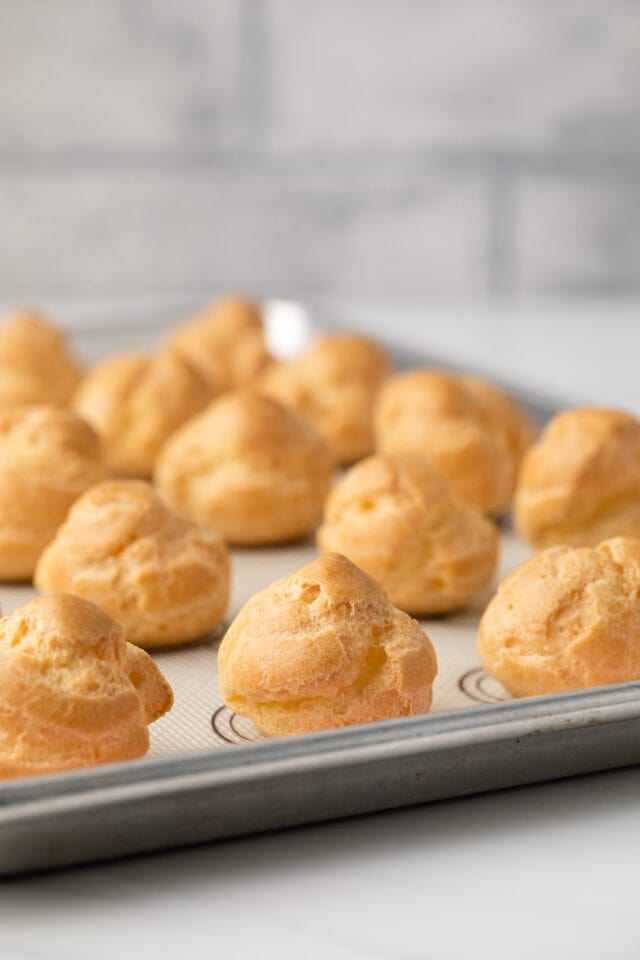 Cream puff shells on a baking sheet.