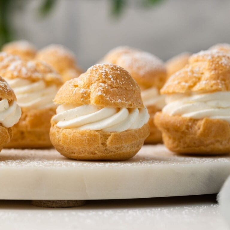 Homemade cream puffs on white stand.