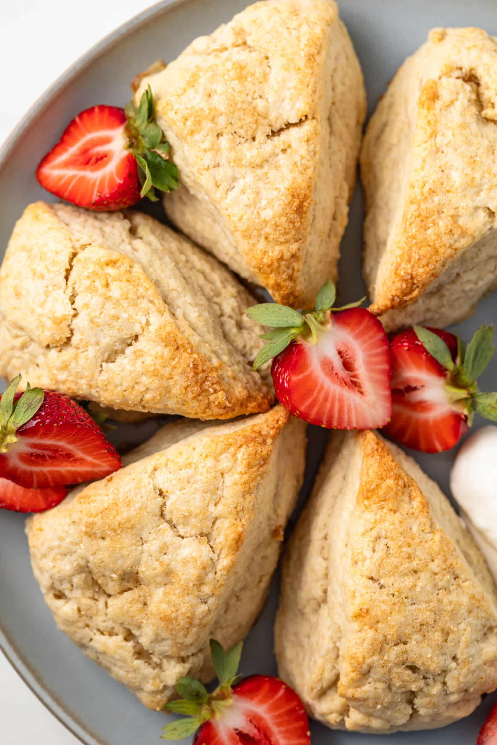 Close up of plate of cream scones with strawberries.