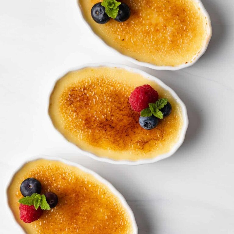 overhead of three ramekins with creme brulee and fresh berries