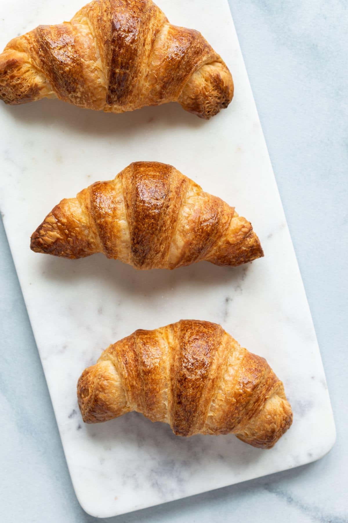 Overhead view of three croissants on a marble slab