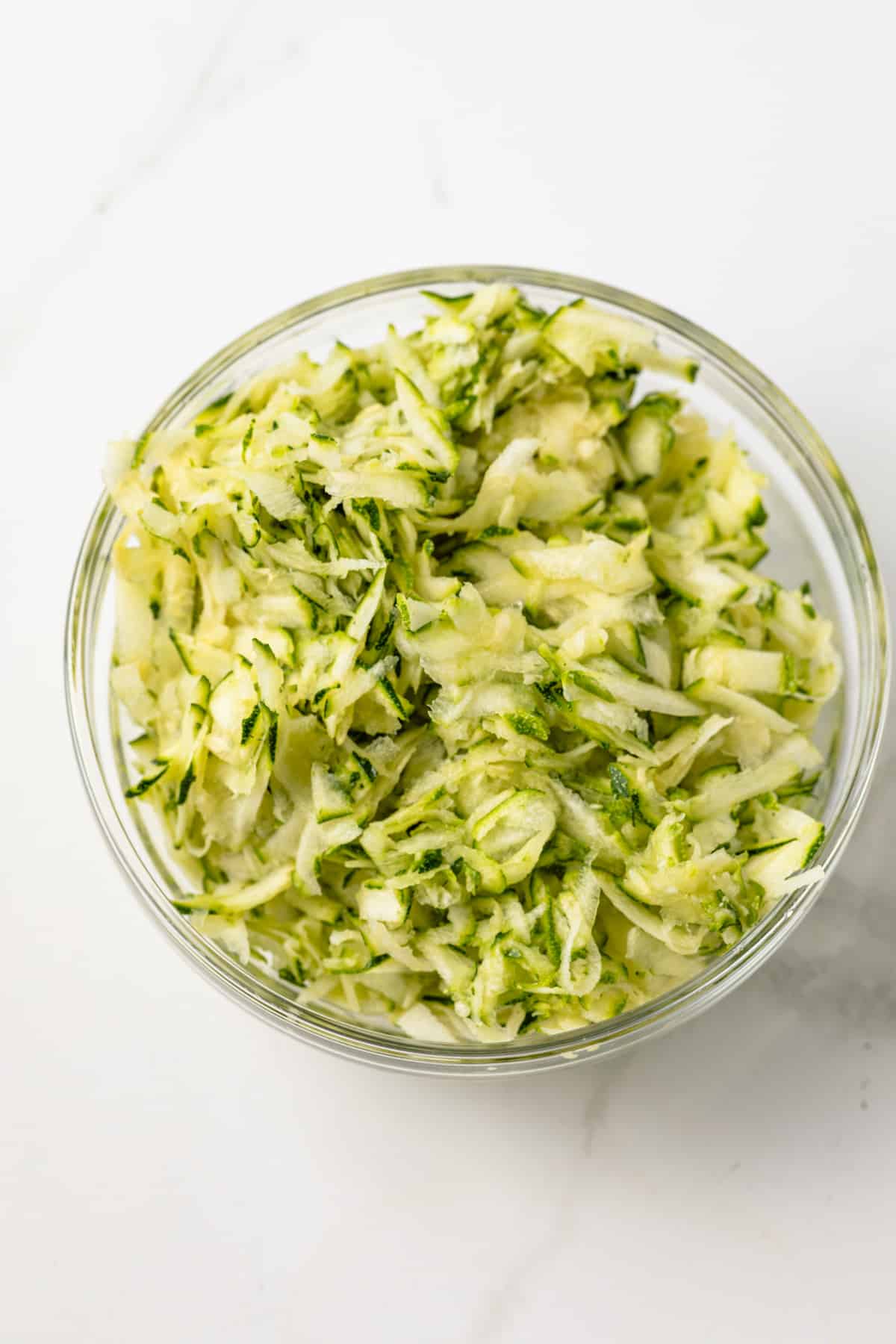 Shredded zucchini in a glass bowl.