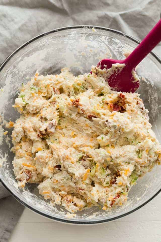 drop biscuit batter with cheese, zucchini, and tomatoes in glass bowl