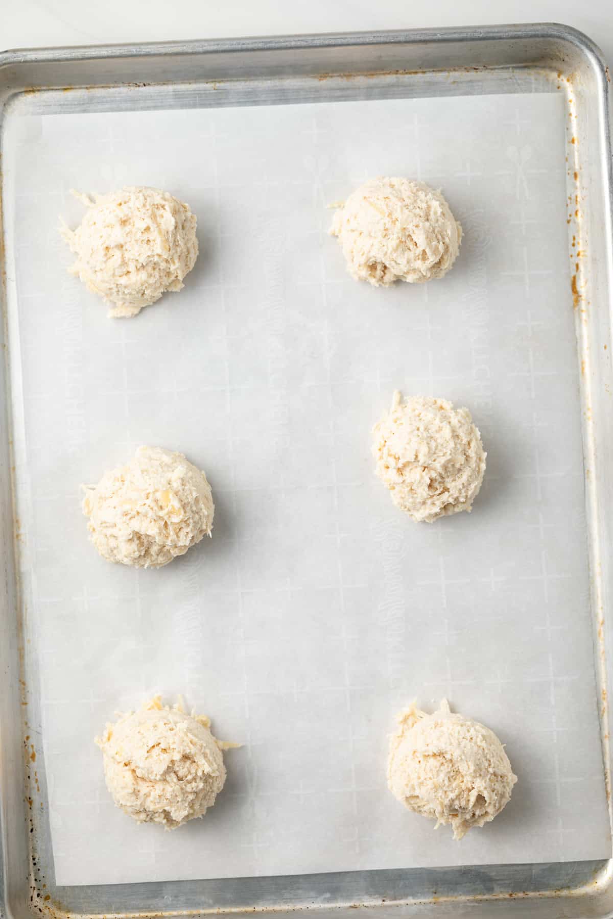 Unbaked drop biscuits on baking sheet.