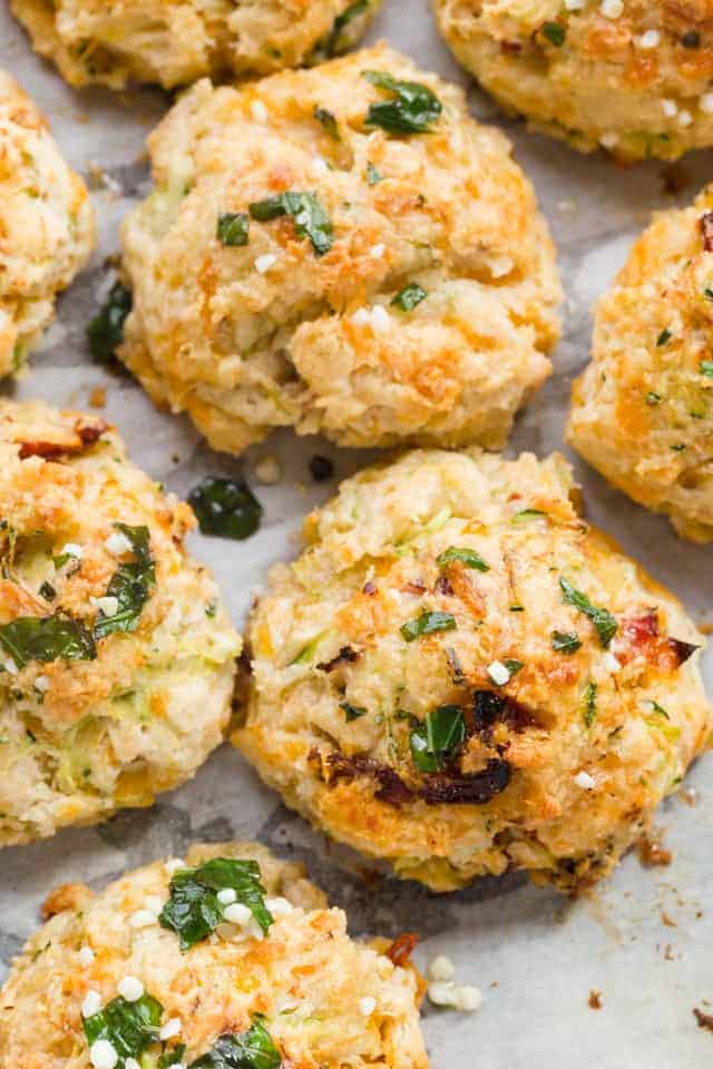Closeup view of Drop Biscuit Recipe with Cheddar Cheese, Zucchini, and Tomato on parchment paper.