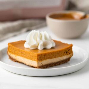 Dulce de Leche Pumpkin Bar on white plate, topped with whipped cream