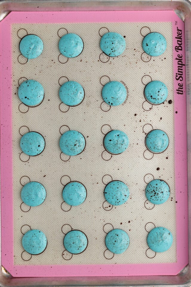Macaron shells with chocolate splatter.