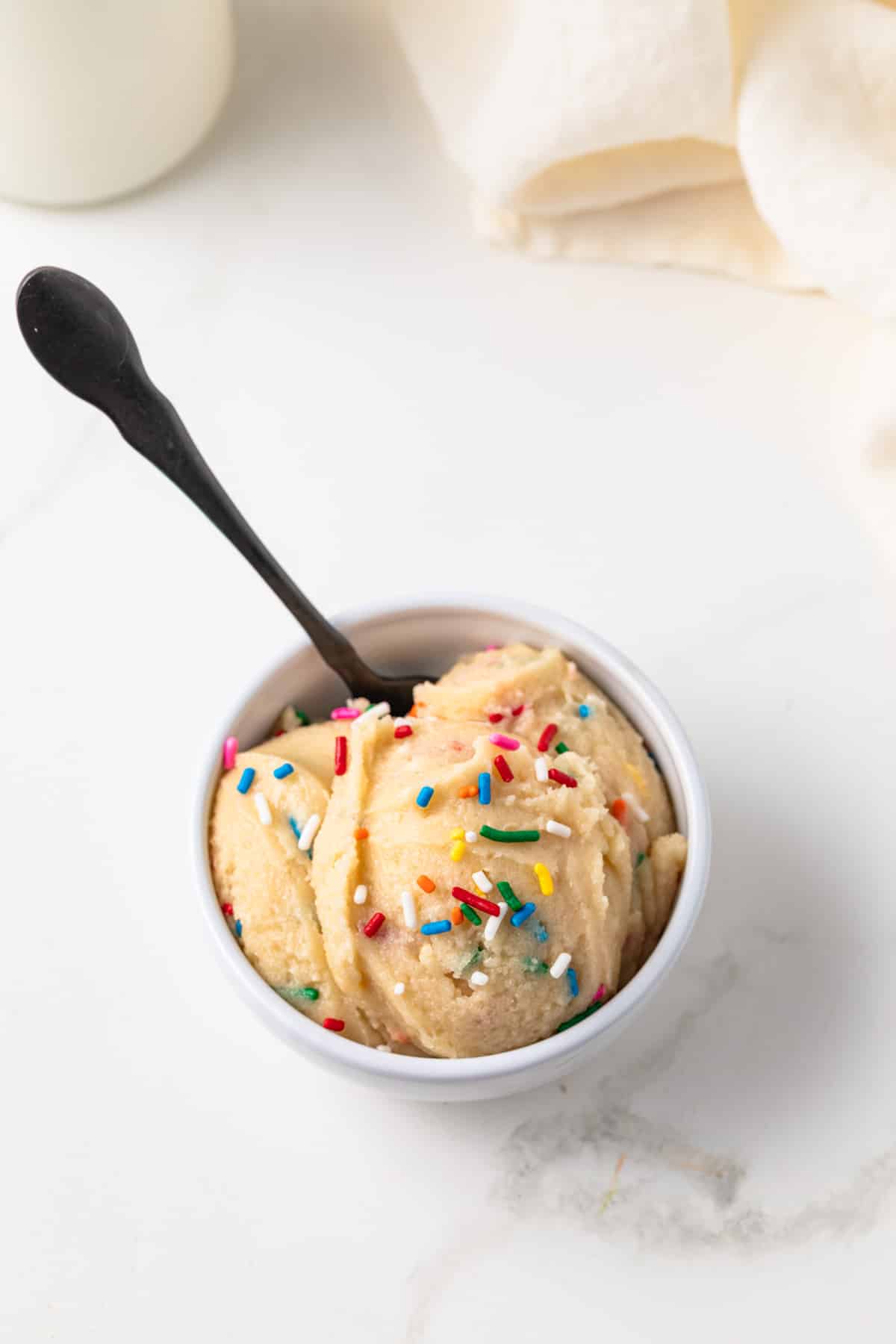Overhead of edible sugar cookie dough in white bowl.