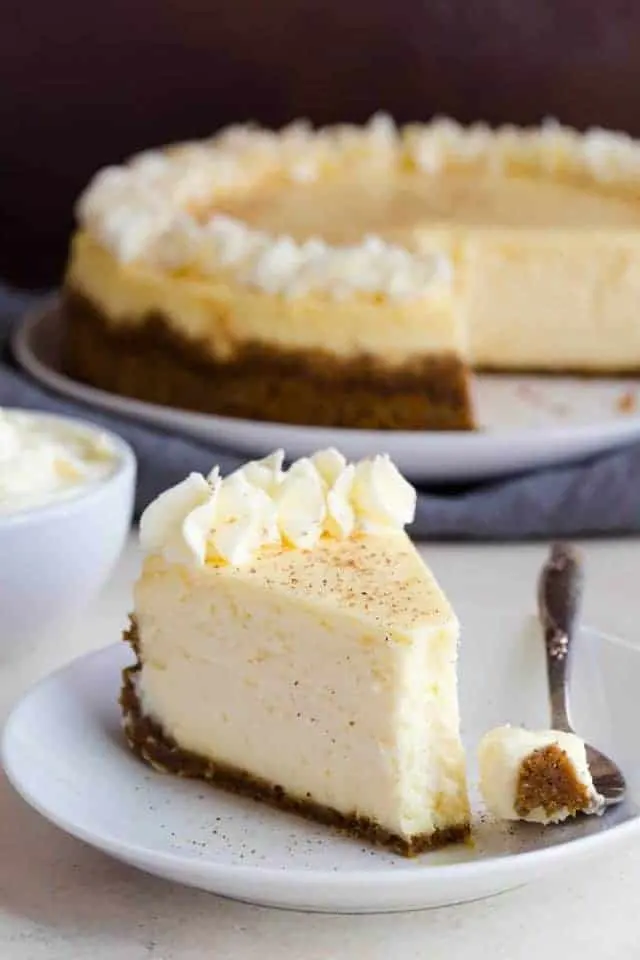 Eggnog cheesecake on white plate with a fork taking a bite out.