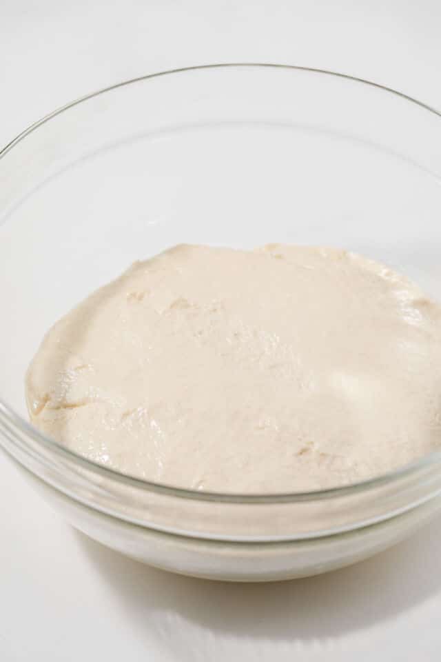 Proofed focaccia dough in glass bowl.
