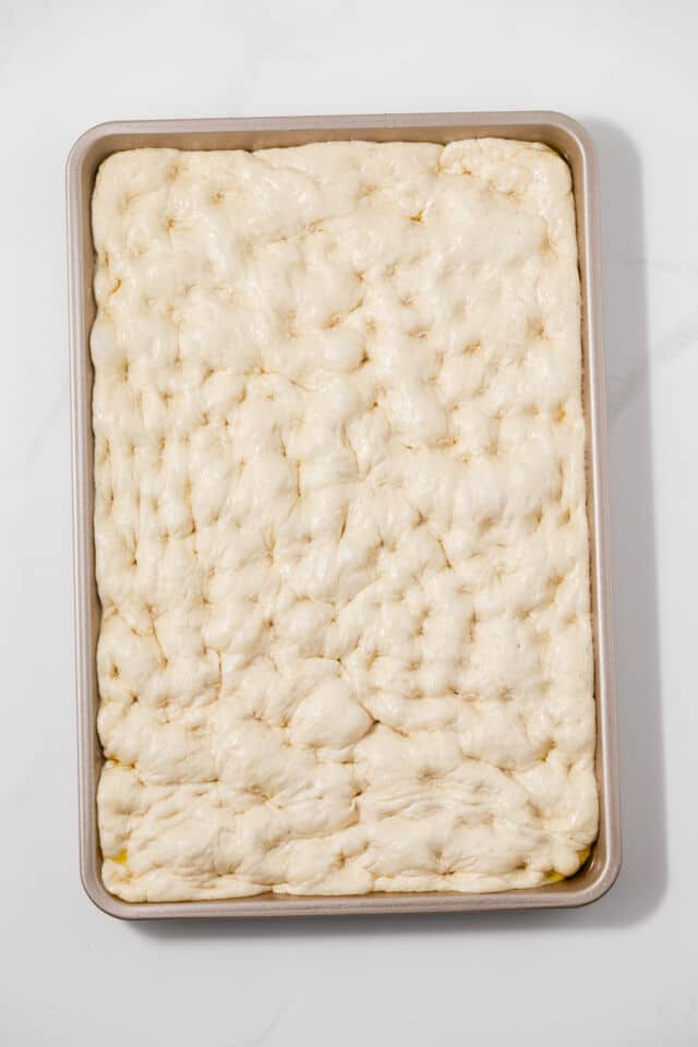Dimpled dough in baking dish.