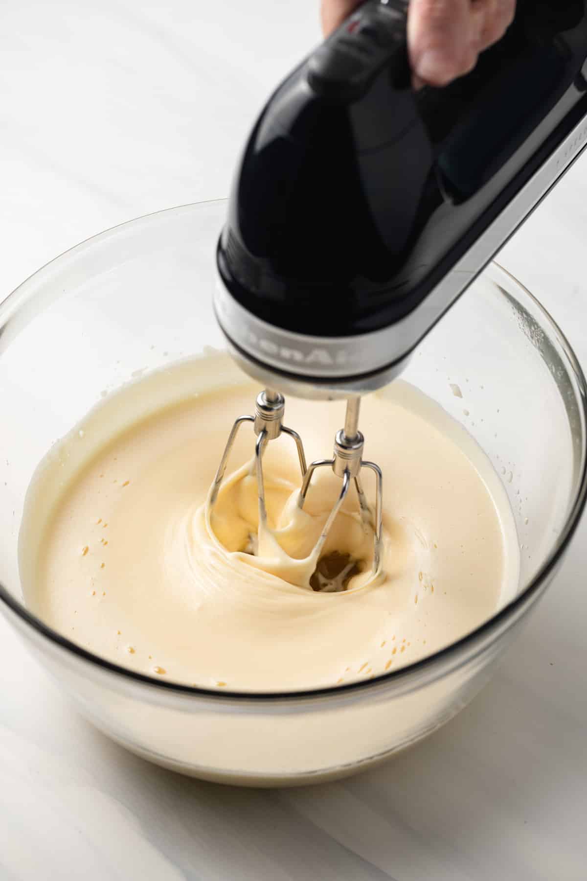 Whipping eggs with sugar in a glass bowl.