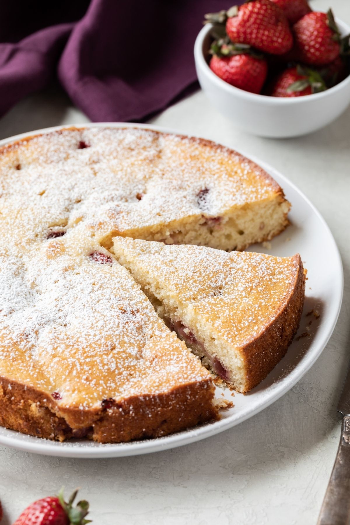 angled view of fresh strawberry cake with a slice cut out