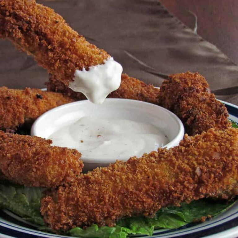 Fried Pickle Spear being dipped in a ramekin of ranch dressing.