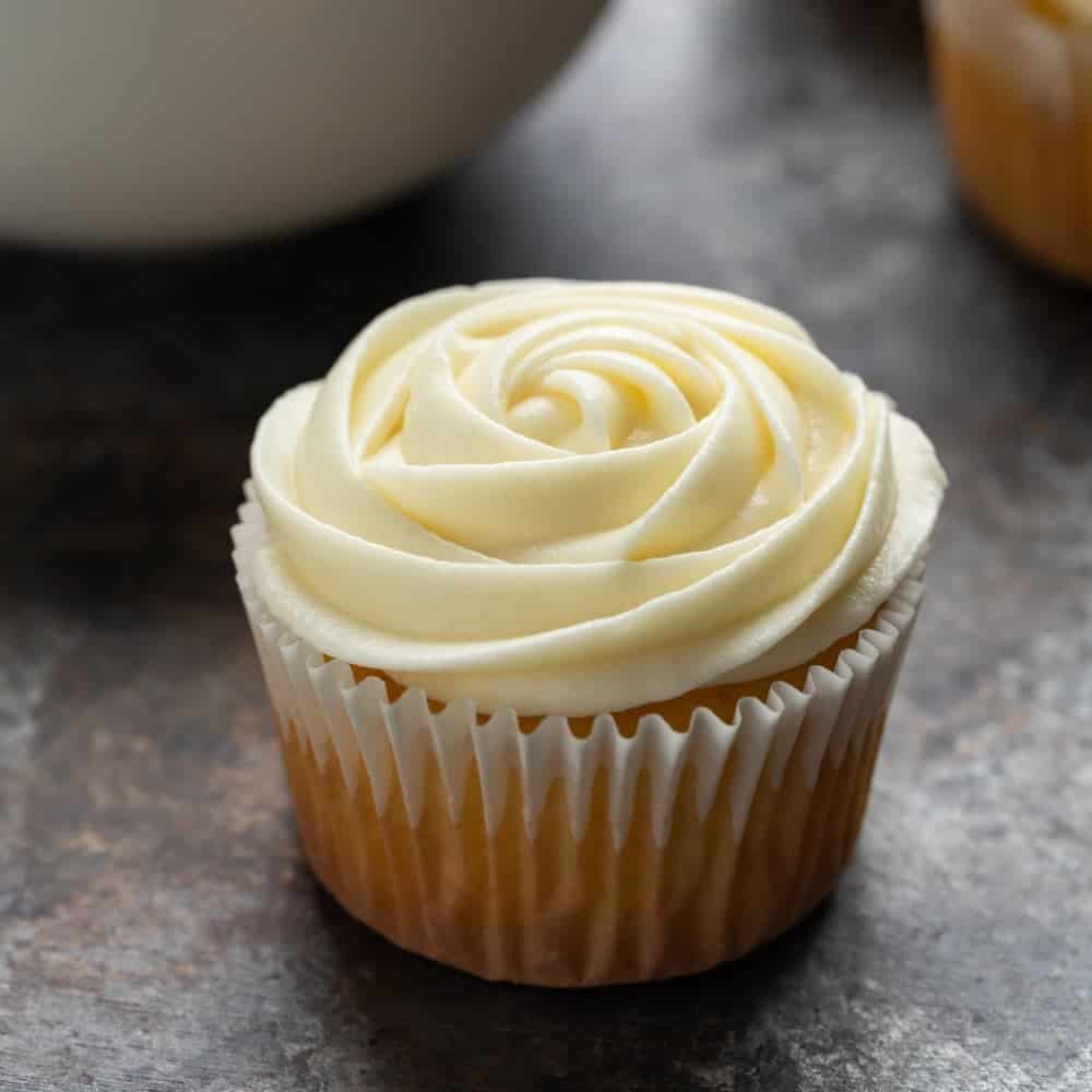 Cream cheese frosting piped in rose design on a cupcake.