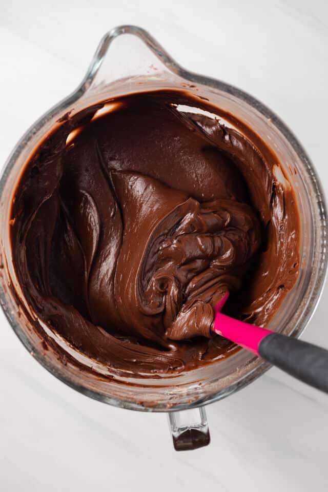 Fudge frosting in a glass mixing bowl.