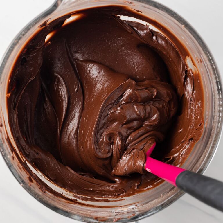 Fudge frosting in a glass mixing bowl.