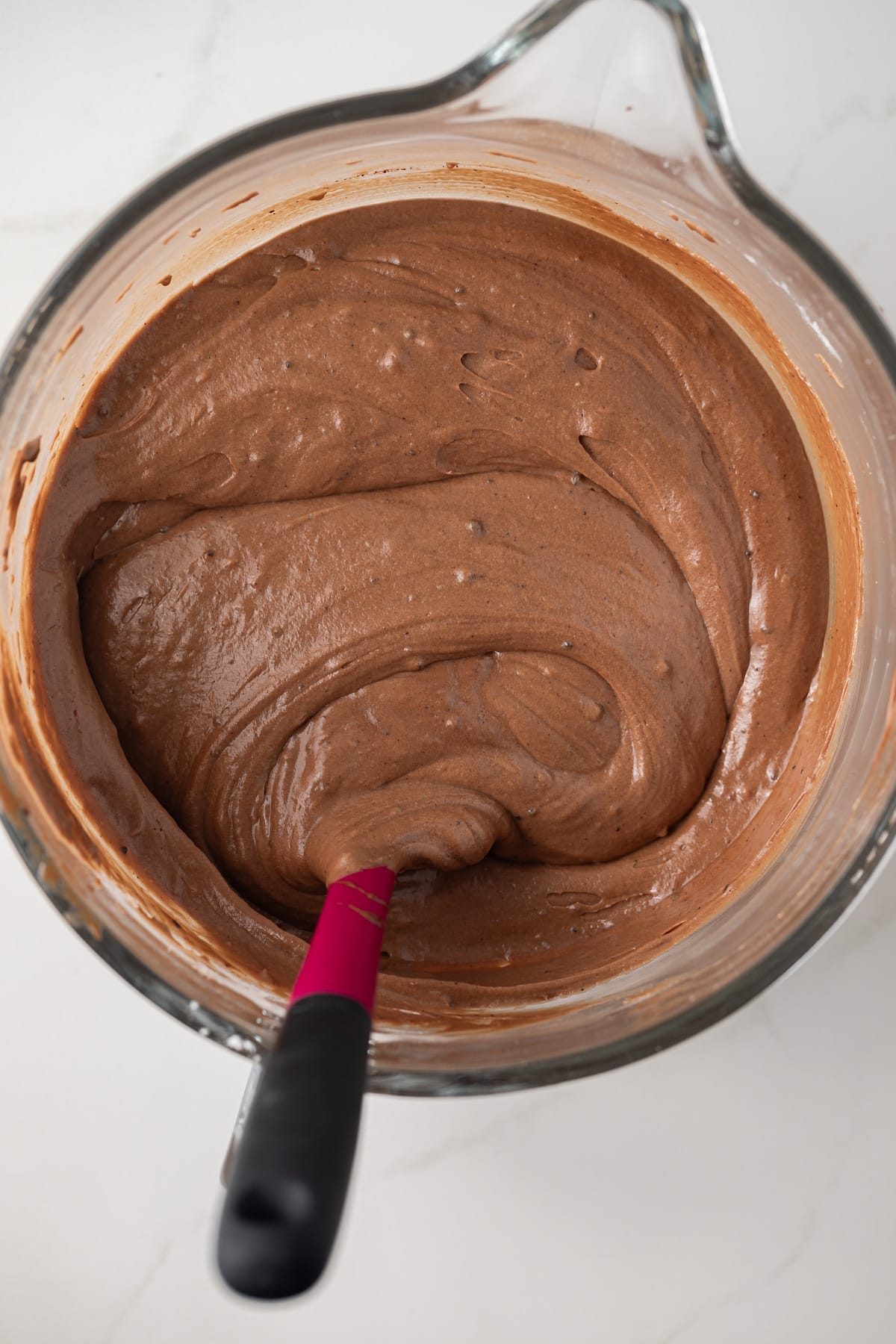 Chocolate cake batter in glass mixing bowl.