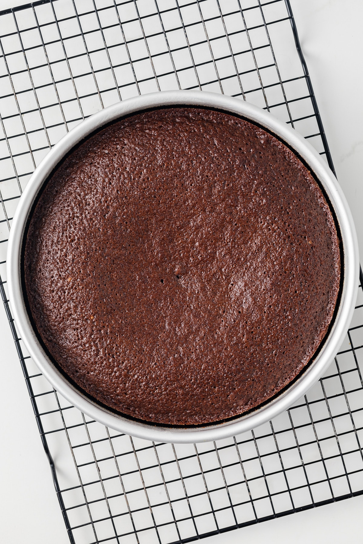 Gingerbread cake in cake pan on wire rack.