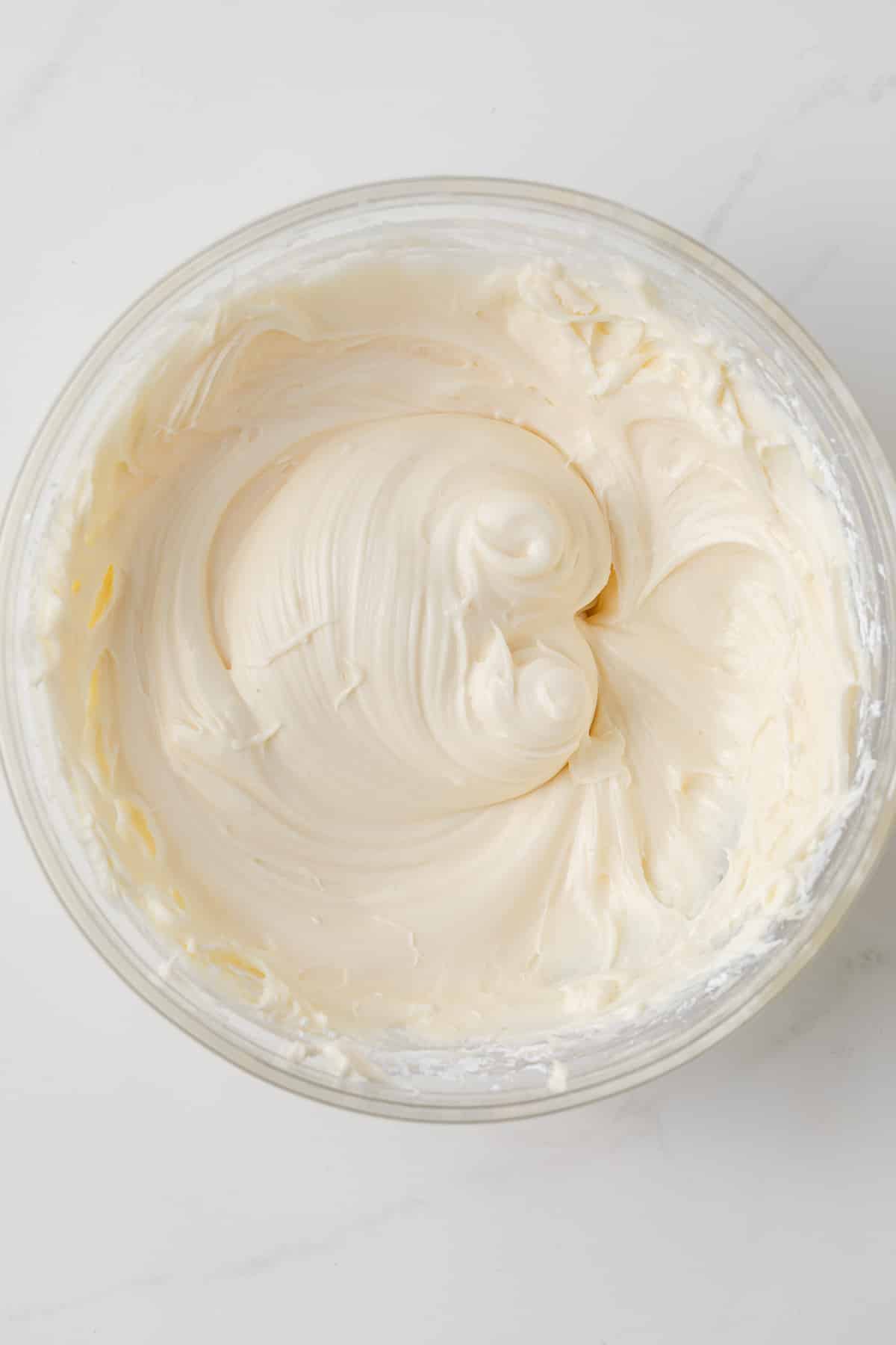 Cream cheese frosting in a glass bowl.