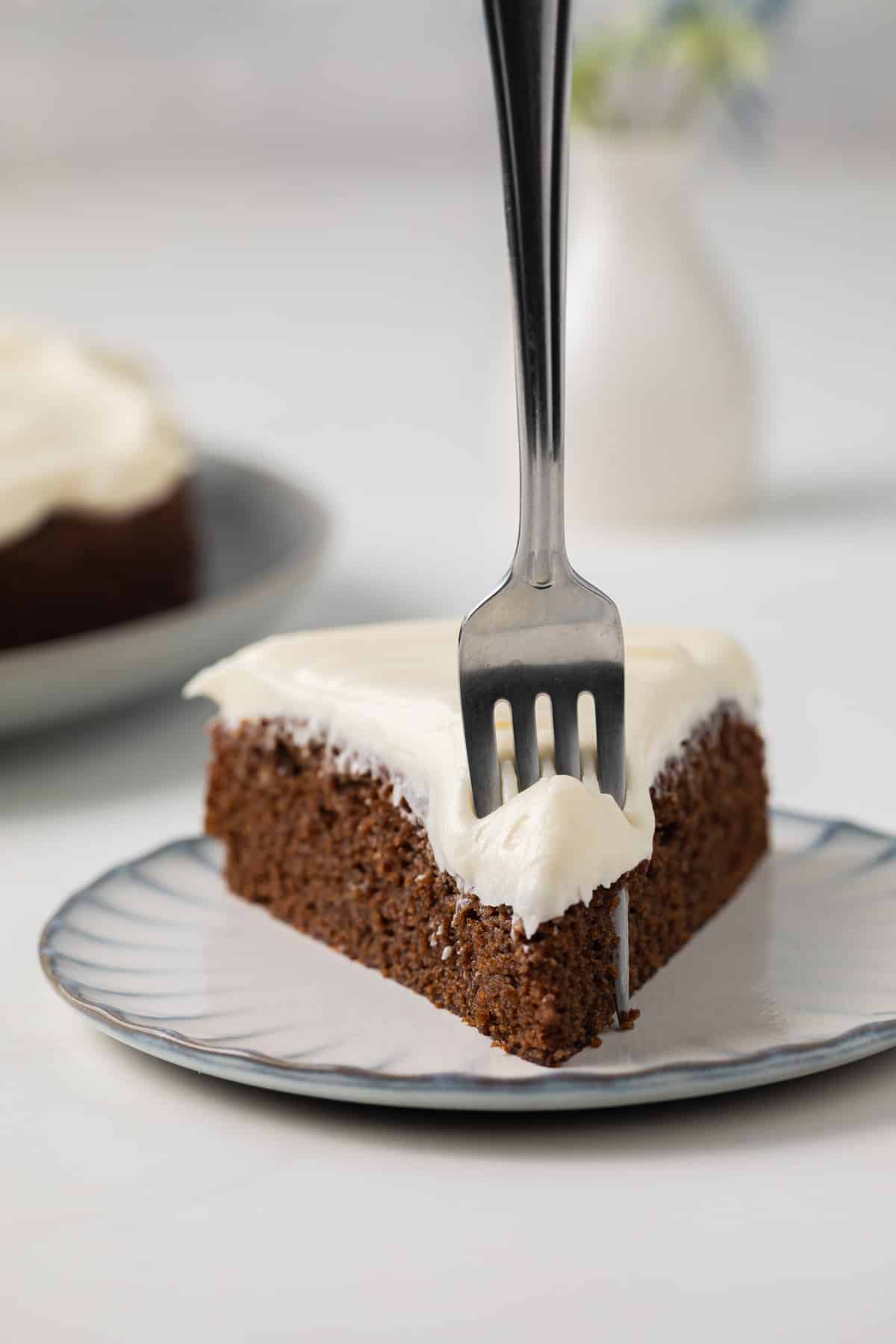 Slice of gingerbread cake with a fork taking a bite out.