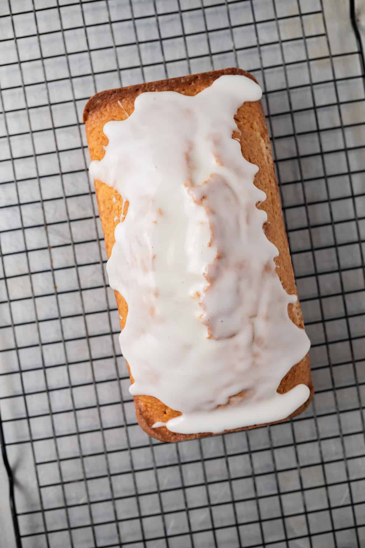 Overhead of glazed lemon bread on wire rack.