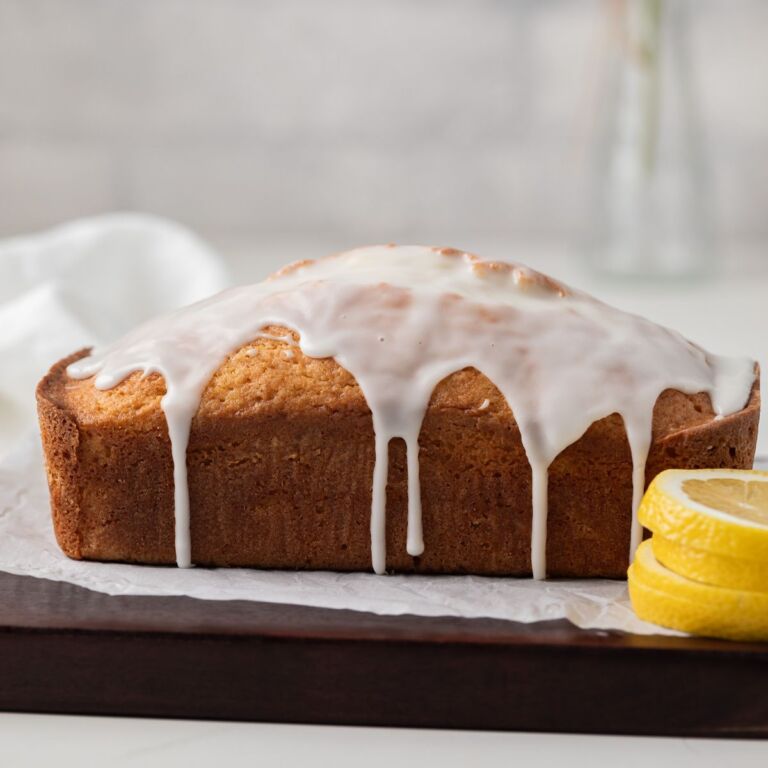 Side view of glazed lemon bread on wood board.