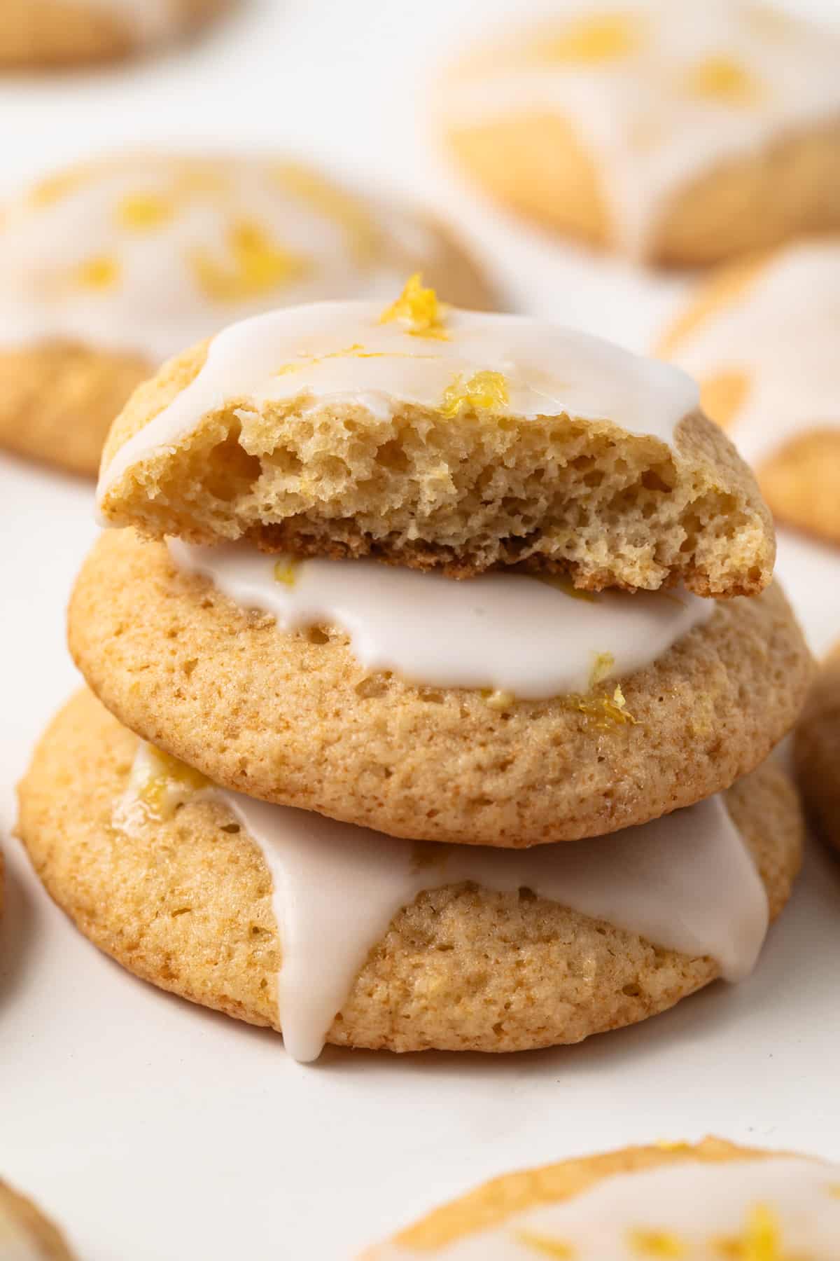 Three lemon cookies stacked with one broken so texture is visible.