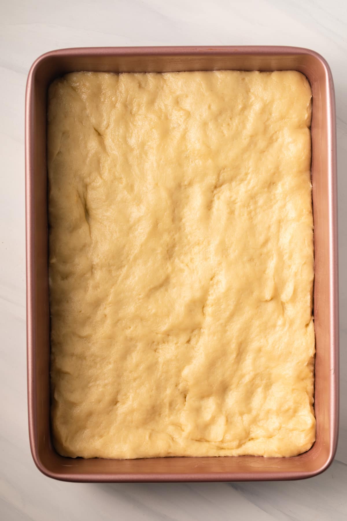 Puffy yeasted cake base in baking pan.