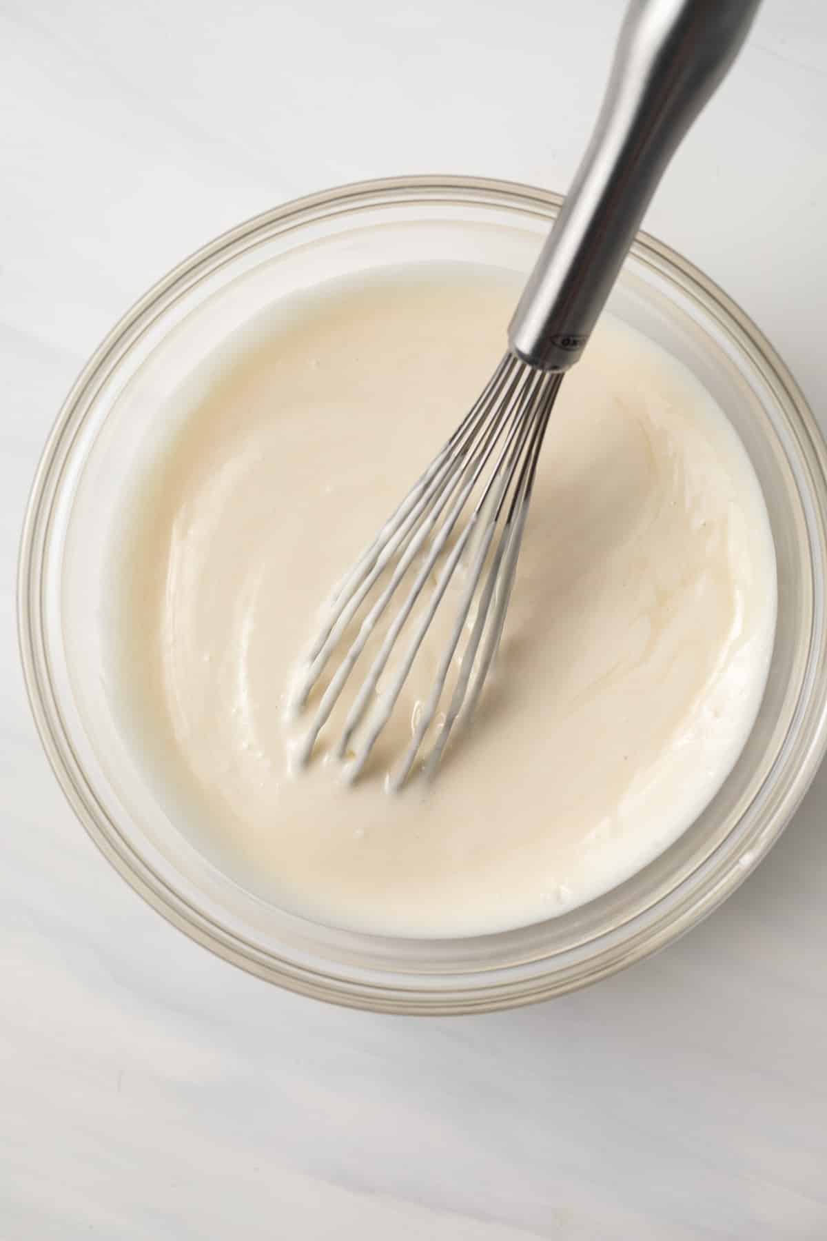 Homemade cake release in a glass bowl with whisk.