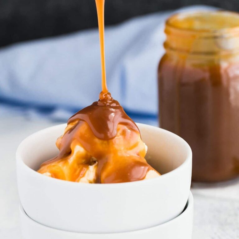 Homemade caramel sauce bring drizzled over a scoop of ice cream in a white bowl.