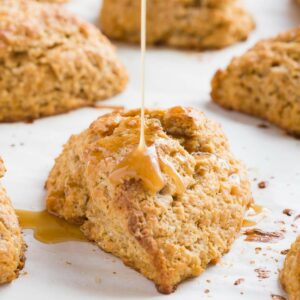 Honey citrus glaze being drizzled over baked sweet potato scones.