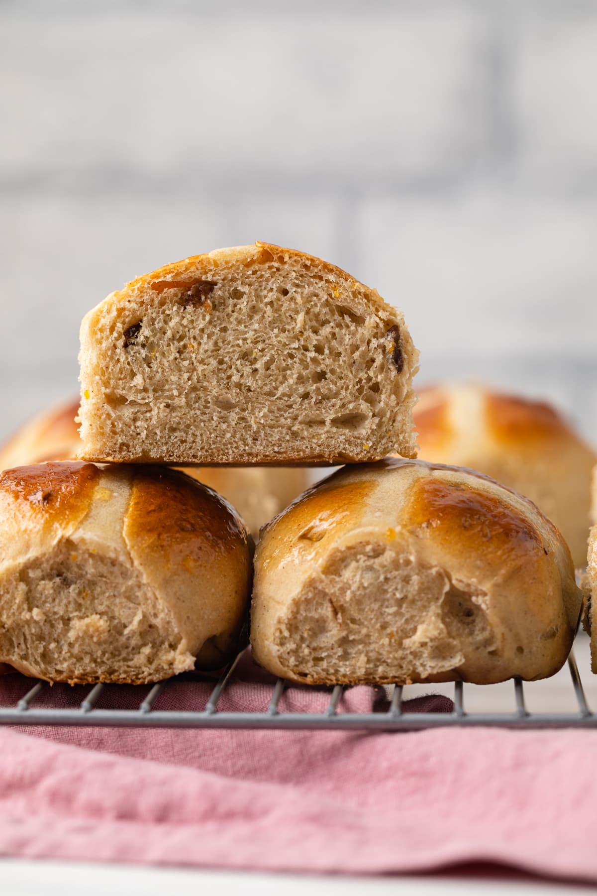 Hot cross buns with one cut open so the inside is visible.